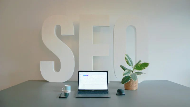 seo strategy workspace with laptop showing analytics in front of large SEO letters