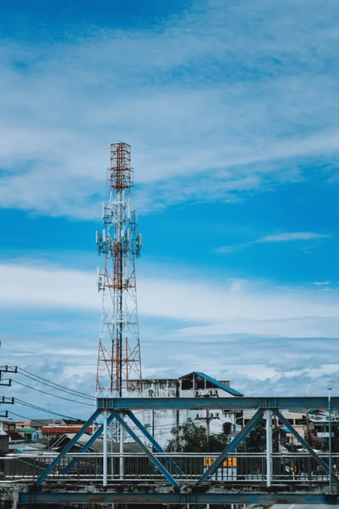 Tall Telecom Tower In City Under Clear Blue Sky