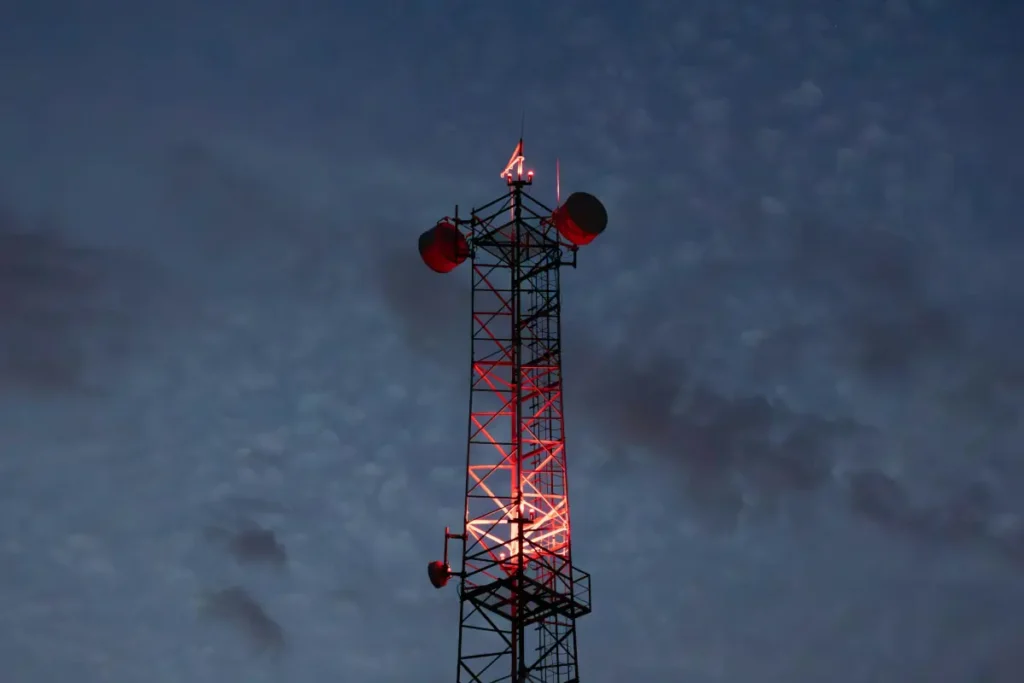 communication tower glowing red lights against night sky