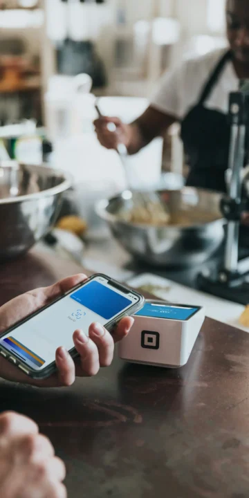 Customer Making A Contactless Mobile Payment Using A Smartphone At A Square Nfc Reader Inside A Small Business Shop