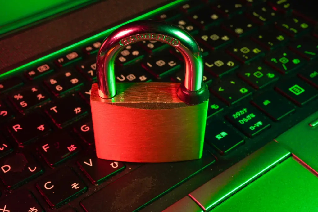Padlock resting on a laptop keyboard illuminated with red and green lighting, representing data protection at coffee shop vpn