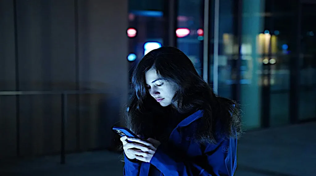 Woman using smartphone at night symbolizing Xfinity Mobile's Avast Antivirus and mobile cybersecurity protection