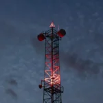 Communication Tower Glowing Red Lights Against Night Sky