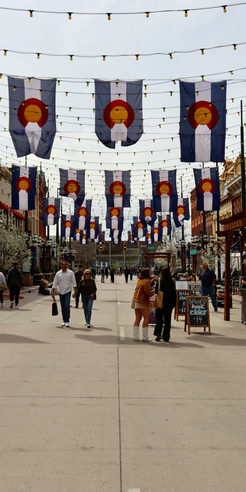 Larimer Square In Downtown Denver Featuring Colorado State Flags And Pedestrians Walking Under String Lights